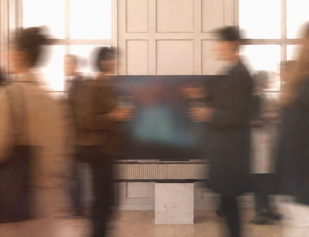 Blurred motion photo of guests standing near a wall-mounted display