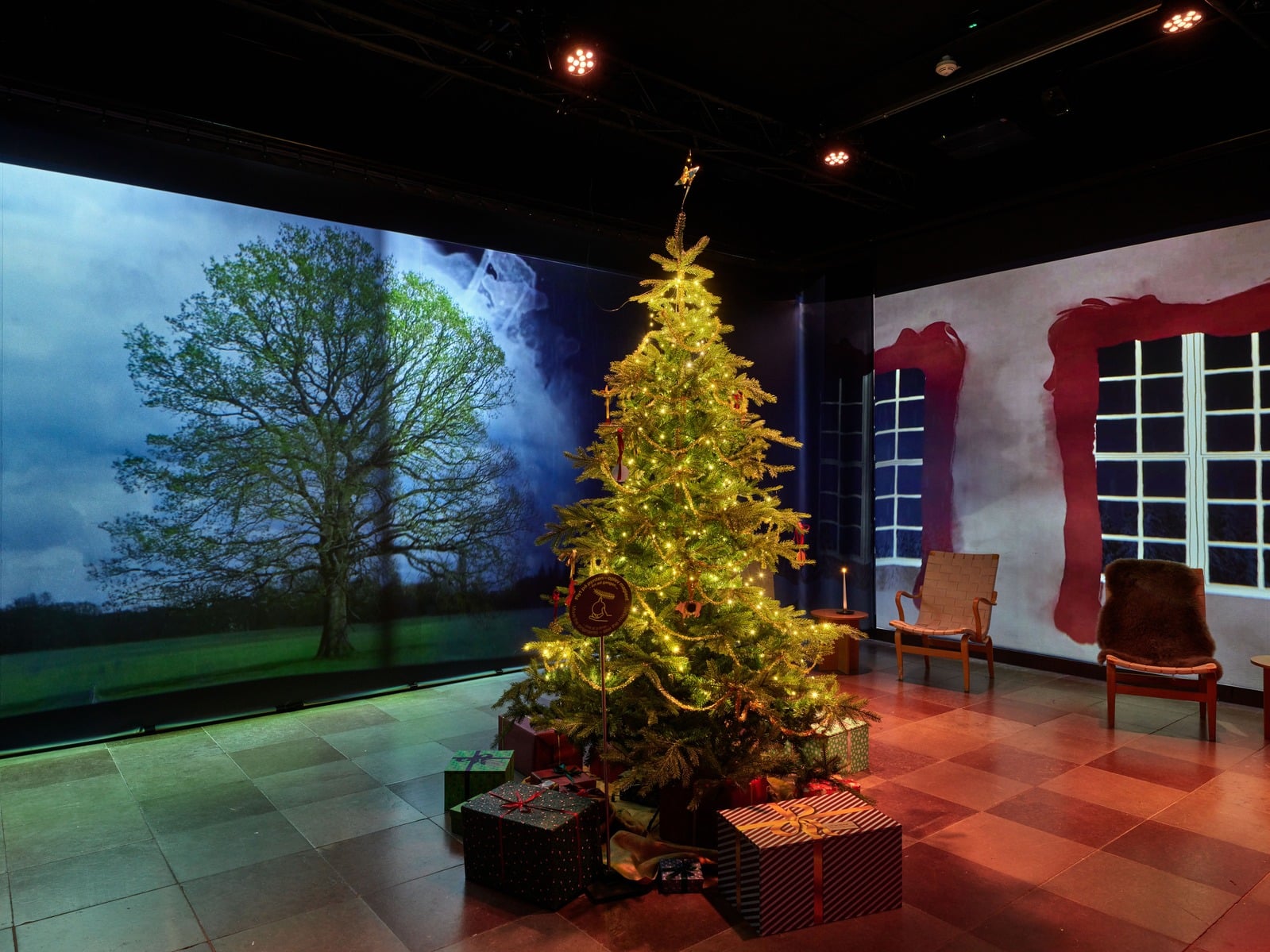 Illuminated Christmas tree exhibit with projected tree and window scenery on surrounding screens